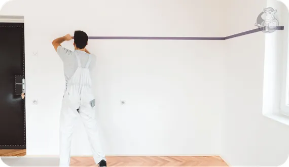 mężczyzna wyznaczający linię niebieską taśmą malarską